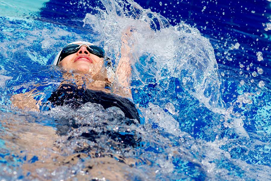 Young woman swimming back stroke