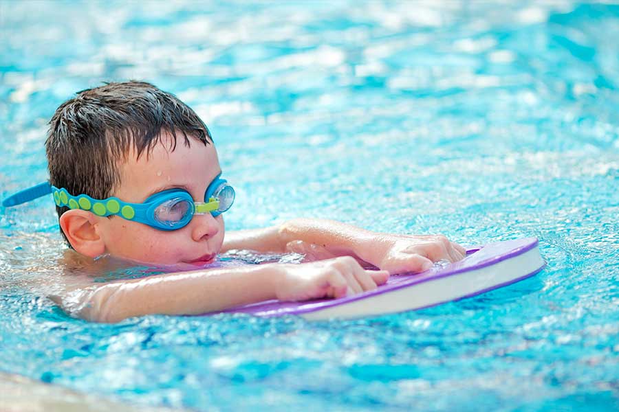 Young boy swimming with a float