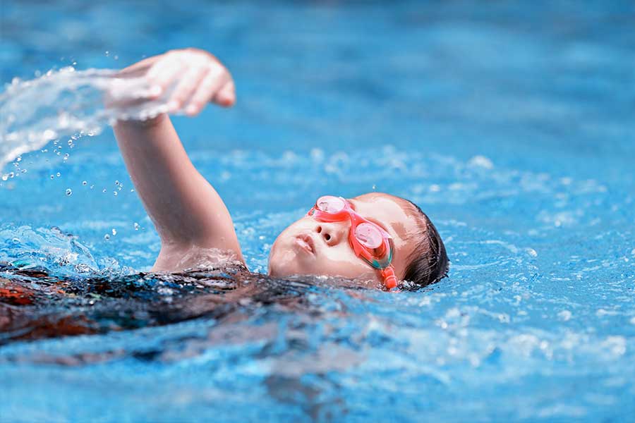 Girl swimming wearing red goggles