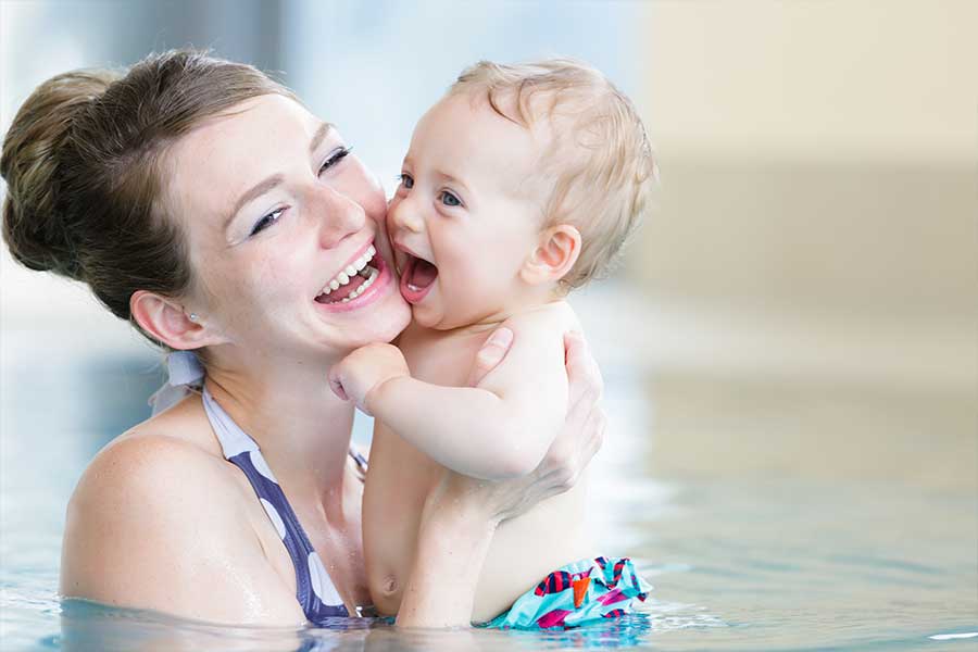 Toddler cuddling mum in swimming pool