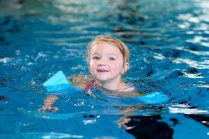 Young girl swimming with blue armbands