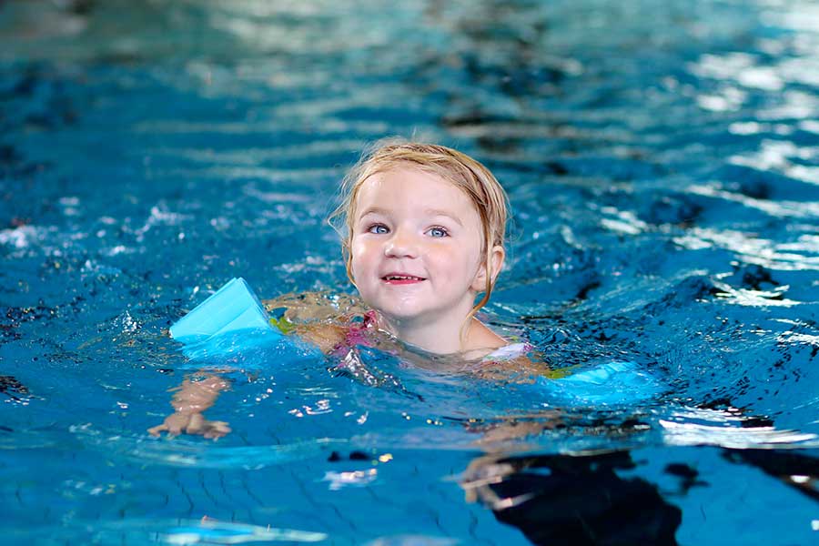 Young girl swimming with blue armbands